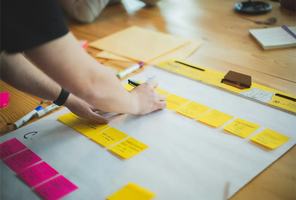 A person is seen working on a project, using sticky notes to visually organize and streamline their workflow.