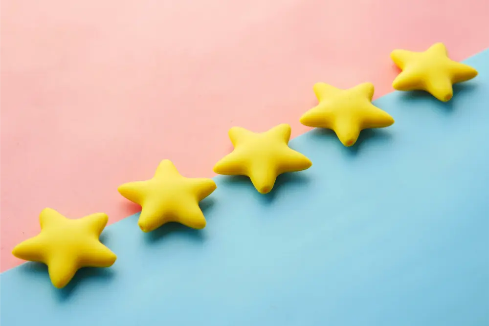 A collection of five yellow star-shaped toys on a blue and pink background, illustrating five-star ratings.