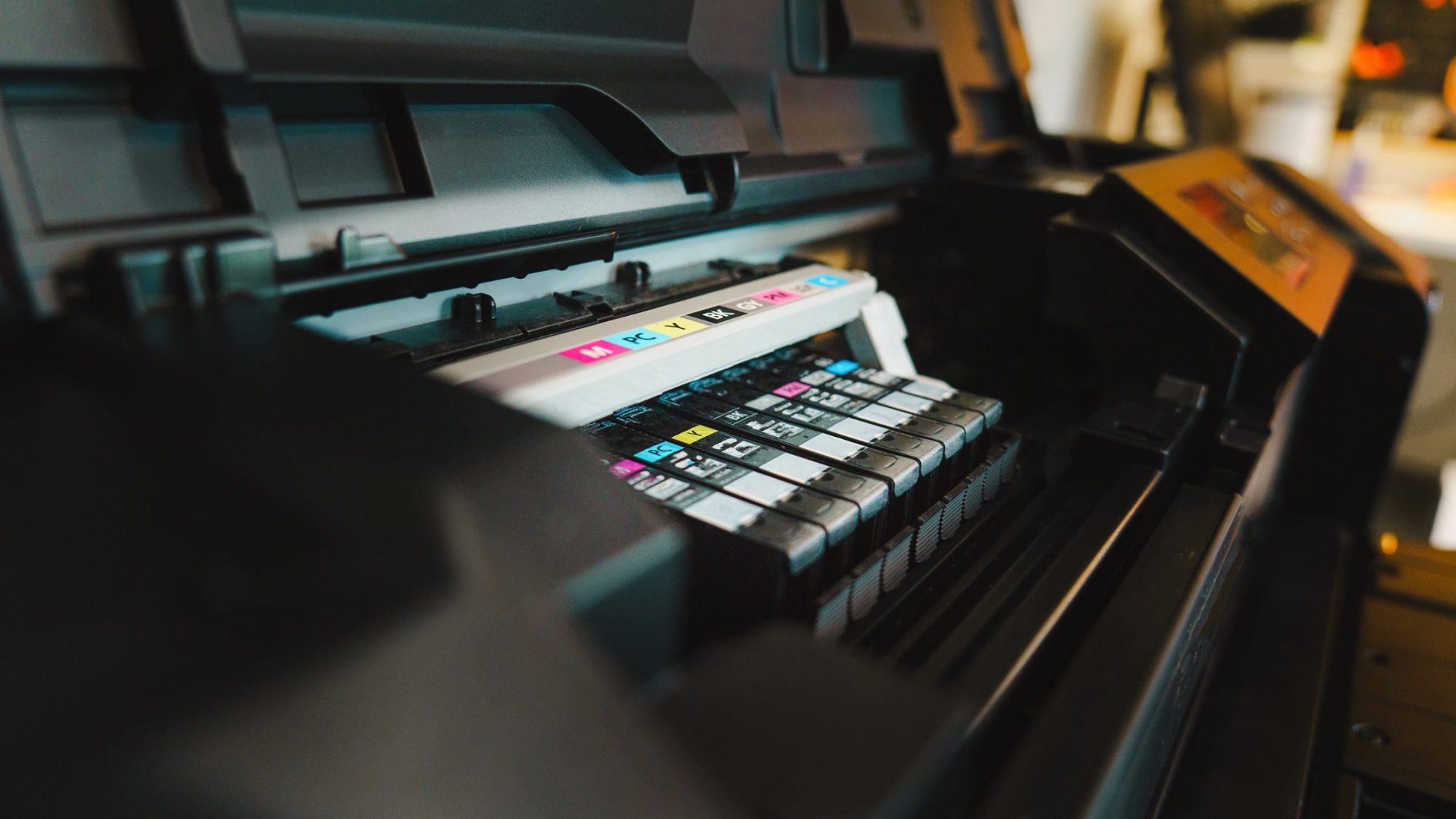 Close-up of an open printer with visible ink cartridges in various colors, including magenta, yellow, cyan, and black.
