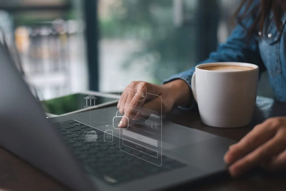 A person using a laptop with a holographic display of a login interface appearing above the keyboard.