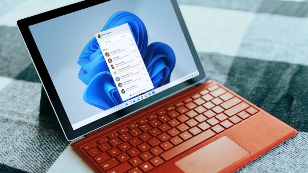 A laptop with an orange keyboard displays the Windows 11 interface on its screen.