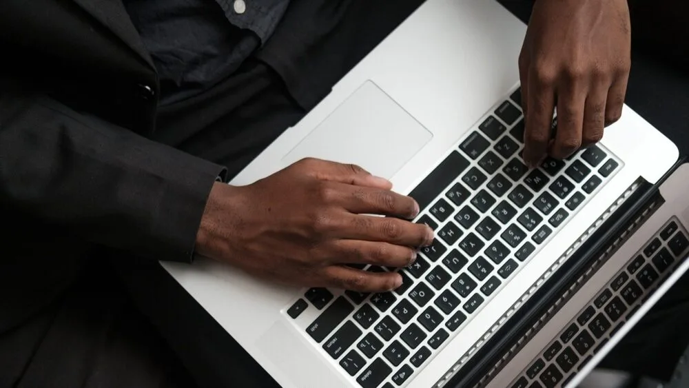 A close-up shot of a person typing on a laptop.