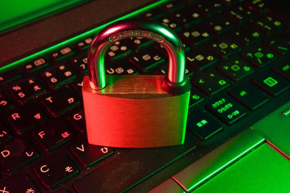 A padlock rests on a laptop keyboard, illuminated by red and green lights, symbolizing cybersecurity.