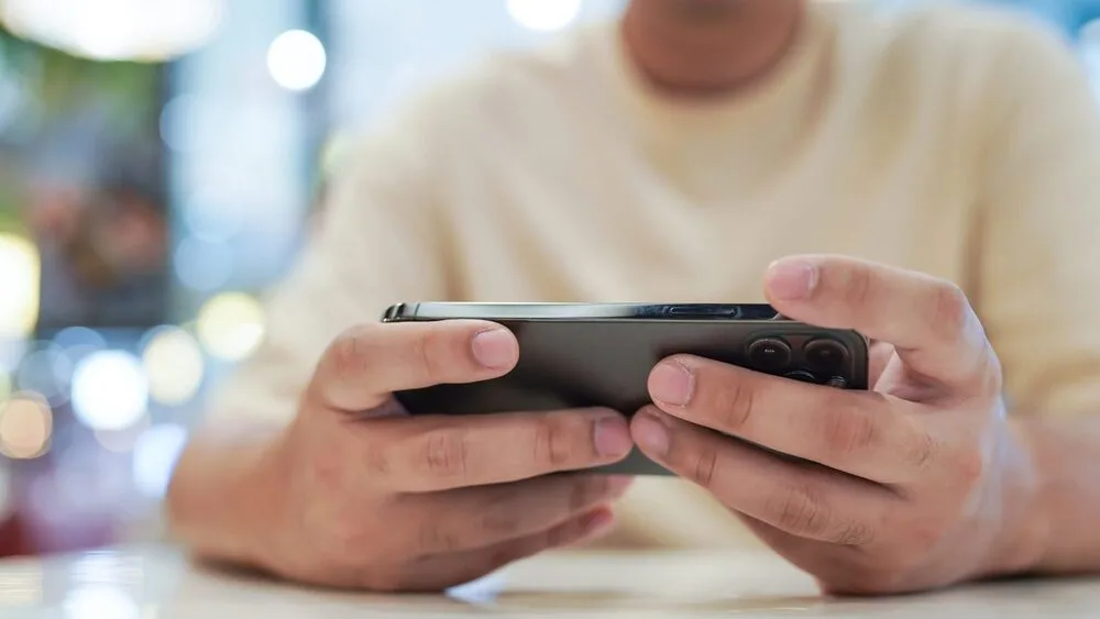 A person is playing a game on a smartphone, holding it in both hands.