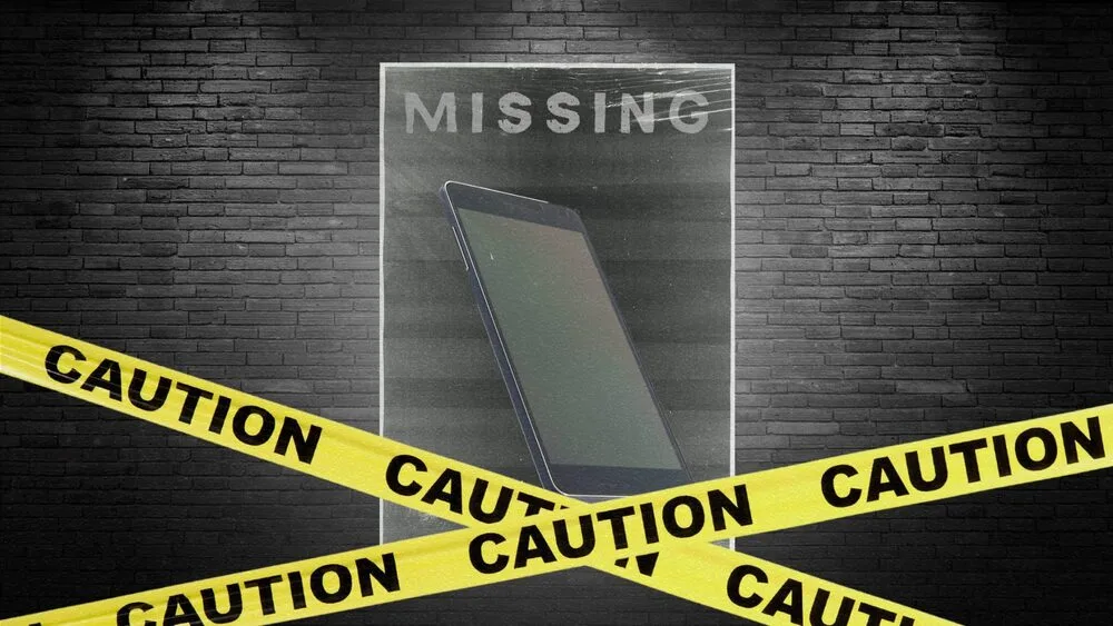 A missing poster with a faint image of a smartphone is taped to a dark brick wall.