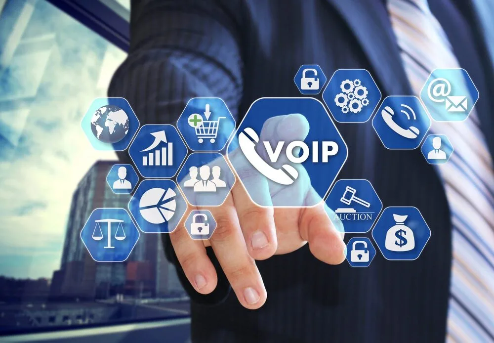 A person in a suit points at a floating virtual interface with various icons, including a graph, globe, people, shopping cart, auction gavel, and a dollar sign.