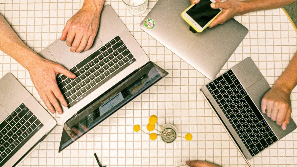 Aerial view of people sitting around a table with laptops. 