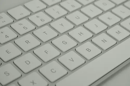 Close-up of a white computer keyboard with clean, evenly spaced keys. The keys are arranged in a QWERTY layout and feature a minimalist, modern design.