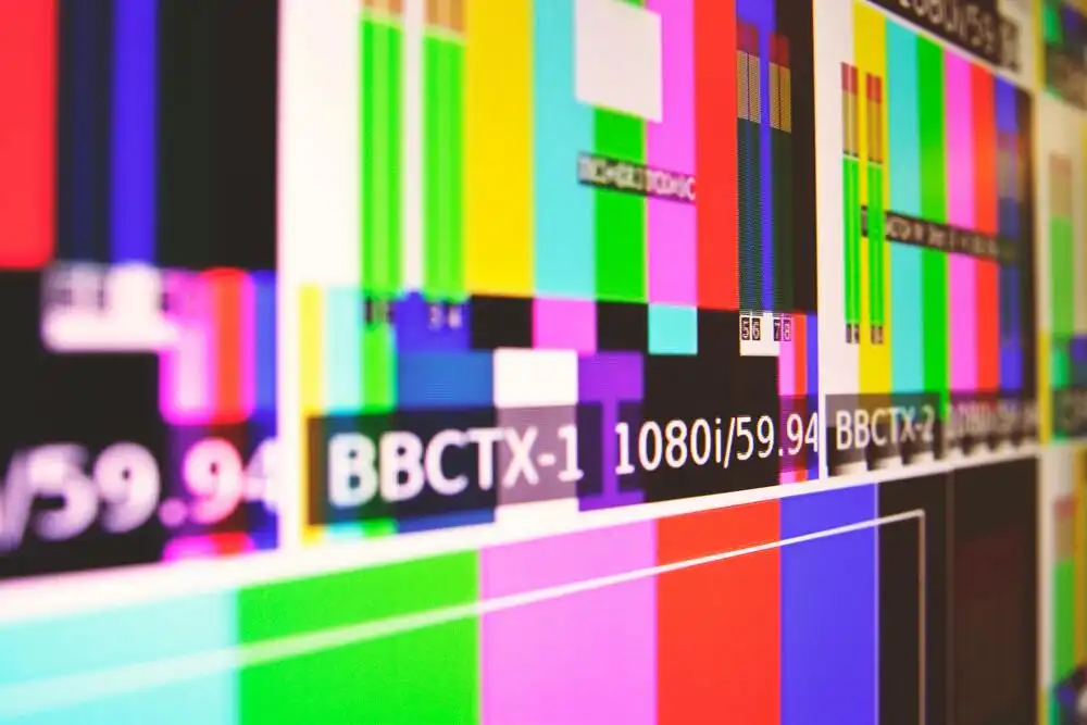 A close-up of a colorful TV test screen displaying various color bars and text, including "1080i/59.94" and "BBCTX-1," against a dark background.