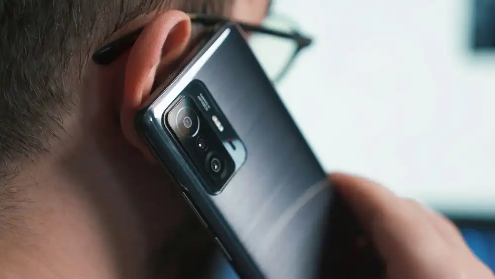 A person holds a smartphone to their ear, as if on a call. 