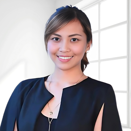 A smiling woman with brown hair tied in a low ponytail stands in front of a large window with white framing. She wears a black top with a unique neckline and a delicate gold necklace. The background is bright and minimalistic.