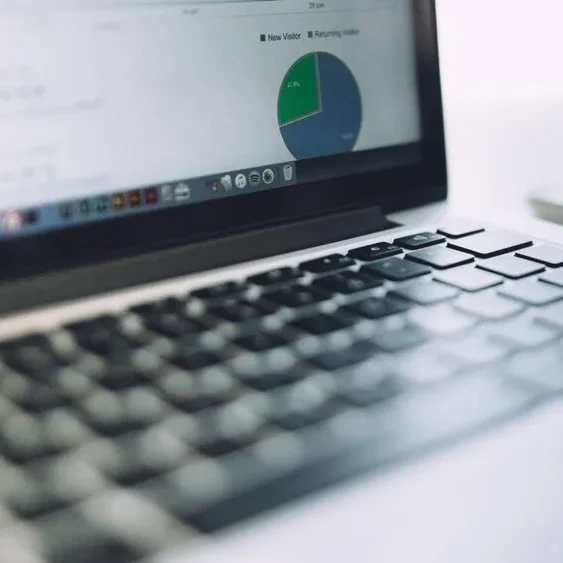 A close-up of a laptop keyboard with an open screen in the background displaying a pie chart and document files.