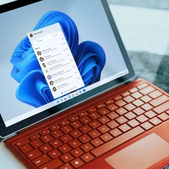 A laptop with an orange keyboard displays the Windows 11 interface on its screen.