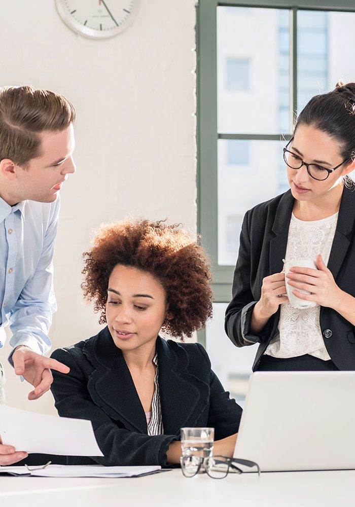 Three people are collaborating in a bright office.