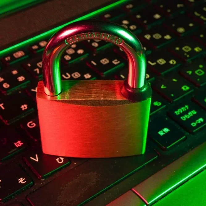 A padlock rests on a laptop keyboard, illuminated by red and green lights, symbolizing cybersecurity.