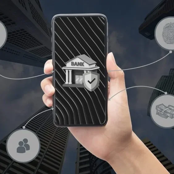 A hand holds a smartphone displaying a bank building icon with a checkmark.