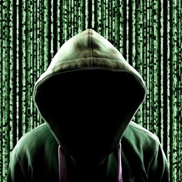 A person in a dark green hoodie stands against a backdrop of cascading green digital code, reminiscent of a matrix style.