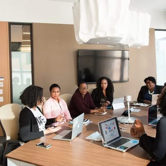 A group of people are sitting around a conference table in a modern meeting room.