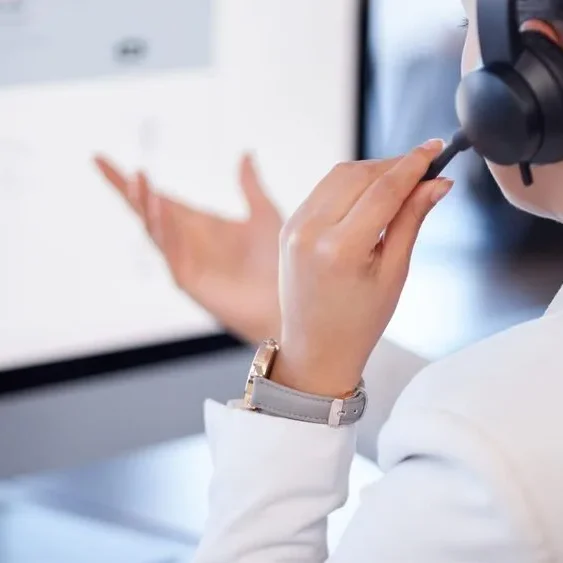 A person wearing a headset is sitting at a desk, facing a computer screen.